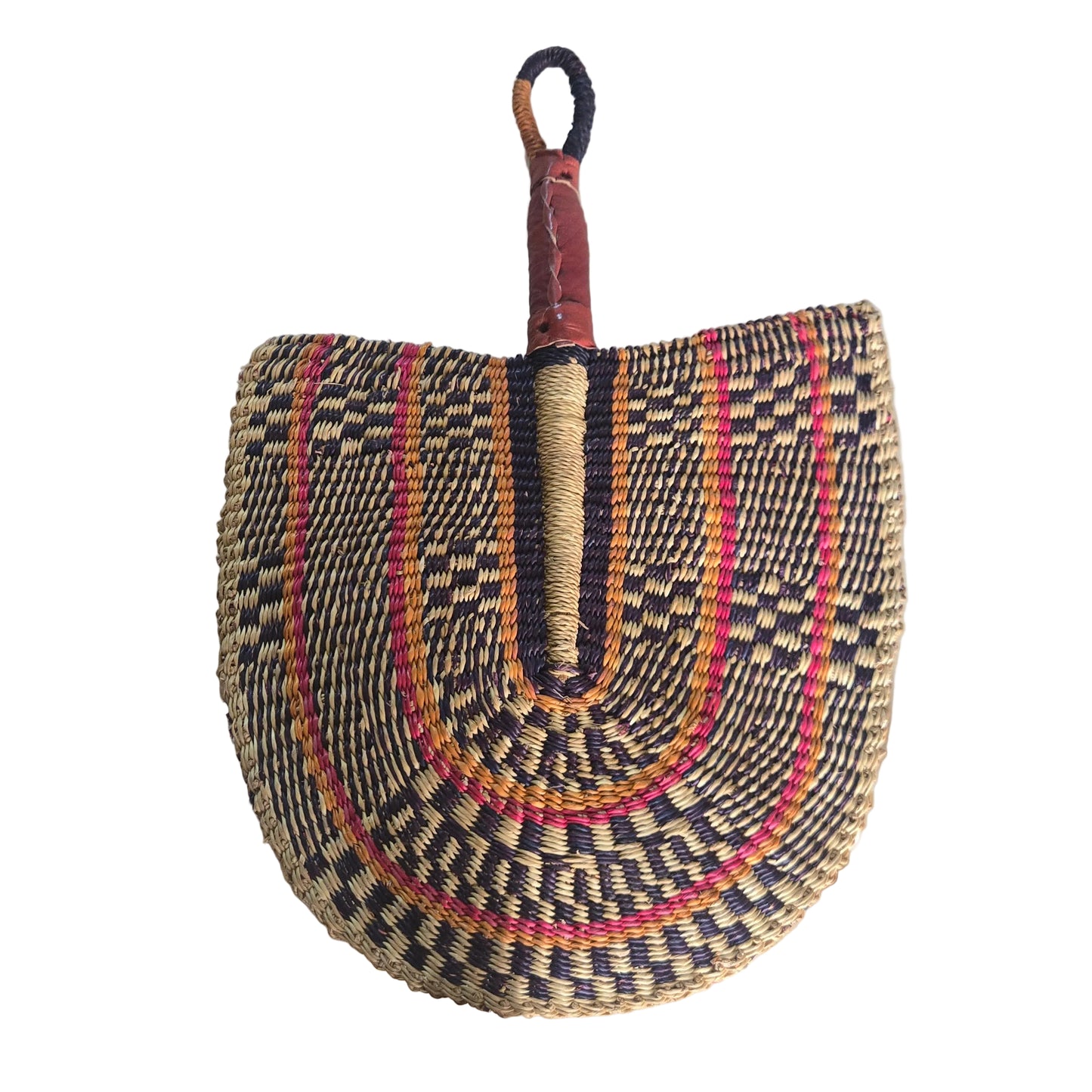 A hand-woven straw fan with a brown leather handle, featuring concentric patterns of black, red, orange, and beige, resting on a white plastic tub in an indoor setting.