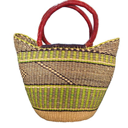 A woven straw tote bag with dark brown and lime green geometric stripes and thick red handles. 